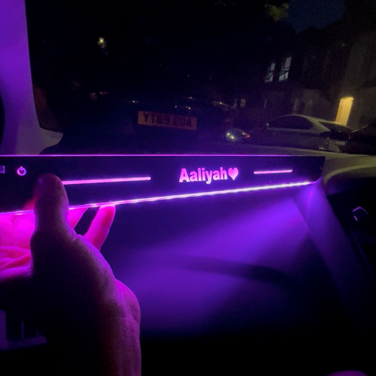 Car interior with a personalized dashboard light bar in the dark.
